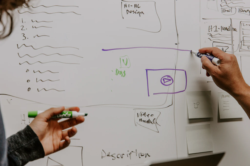 Hände skizzieren eine Struktur mit Listen und Feldern auf einem Whiteboard
